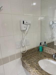 a bathroom with a sink and a hair dryer at Flat Tropical in Manaus