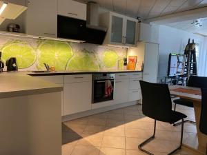 a kitchen with white cabinets and a table with a chair at Haus am See in Braunschweig