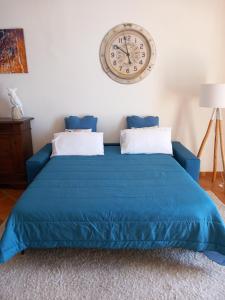 a bedroom with a blue bed with a clock on the wall at Terrazza Miracapri in Pozzuoli +158 photos