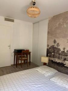 een slaapkamer met een bed en een tafel en een schilderij bij Appartement très calme avec jardin plein sud in Lyon