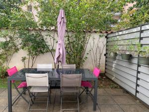 een tafel met roze stoelen en een parasol bij Appartement très calme avec jardin plein sud in Lyon