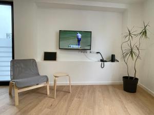 a living room with a chair and a television on a wall at Living PDL 2 in Ponta Delgada