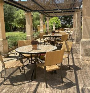een patio met tafels en stoelen onder een pergola bij Agroturisme Son Cardaix in Artá