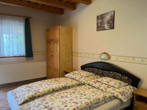 a bedroom with a bed with a comforter and a window at Ibolya Vendégház in Kehidakustány