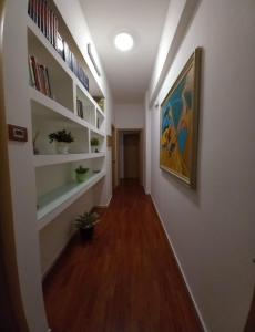 un corridoio con scaffali bianchi e un dipinto sul muro di Le Stanze di Nonna Lina a Pagani