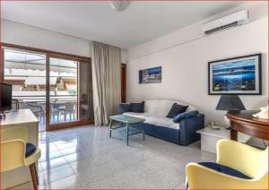 Una sala de estar con un sofá azul y una mesa. en Appartamenti La Colombaia, en Porto Azzurro