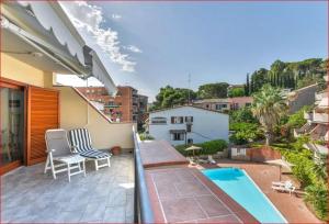 Un balcón con dos sillas y una piscina. en Appartamenti La Colombaia, en Porto Azzurro