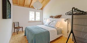 a bedroom with a bed and a chair and a window at Casa de Arcos in Anadia
