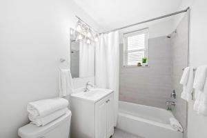 a white bathroom with a sink and a toilet and a tub at The Ambassador Hotel in Palm Beach
