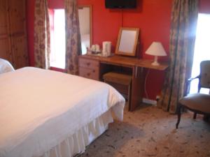 a bedroom with a bed and a desk with a mirror at Castlemaine House B&B in Castlemaine