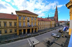 a large yellow building with a clock tower in a city at ELEVEN APARTMENT - very center - free parking in Osijek