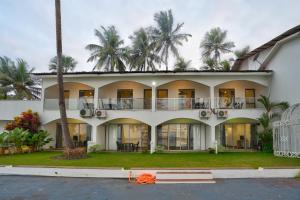 a large white building with palm trees in the background at Blu Missel By The River in Panaji
