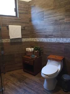 ein Bad mit einem WC und einer Holzwand in der Unterkunft Casa Wayil - Comfort y privacidad en la selva 