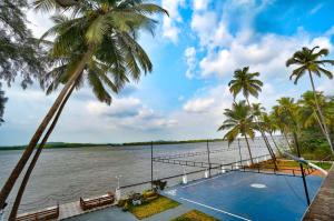 ein Resort mit einem Pool auf dem Wasser mit Palmen in der Unterkunft Blu Missel By The River in Panaji