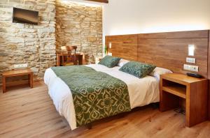 Un dormitorio con una cama grande y una pared de piedra. en Mapoula PR Boutique, en Santiago de Compostela