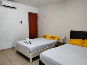 um quarto com 2 camas com lençóis amarelos e brancos em GLOMAR BACALAR em Bacalar