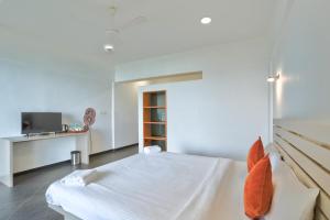 a white bedroom with a bed and a desk at Blu Missel By The River in Panaji