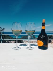 uma garrafa de vinho e dois copos de vinho numa mesa em Amar Seaside em Ksamil