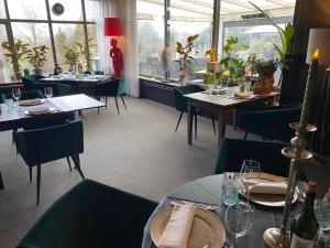 uma sala de jantar com mesas, cadeiras e janelas em De Post B&B Restaurant em Klimmen