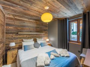 a bedroom with a large bed with a wooden wall at Chalet de prestige au cœur de Saint Martin de Belleville, à quelques pas des pistes - FR-1-570-38 in Saint-Martin-de-Belleville
