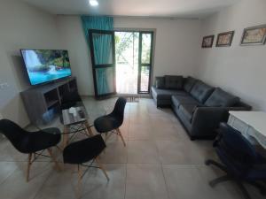 sala de estar con sofá, sillas y TV en Tres Chihuahuas & Spa en Mariano Moreno