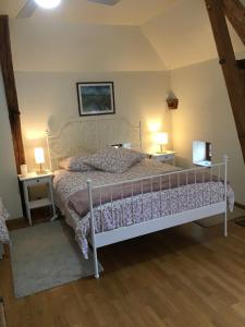 um quarto com uma cama branca com 2 mesas e 2 candeeiros em La Lézardière em Épeigné-les-Bois