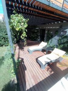 una terraza de madera con 2 bancos encima en Tres Chihuahuas & Spa en Mariano Moreno