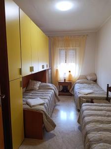 Cette chambre comprend 3 lits et une fenêtre. dans l'établissement Casa Casello alloggio vacanze, à Trappeto