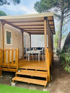 a wooden deck with a table and a dining room at Mobil home 8 personnes camping L'Elysée Vagues Océanes in Le Grau-du-Roi