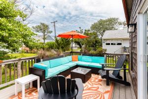 a patio with a blue couch and chairs and an umbrella at Cayuga Street Sunshine Retreat in Ocean Bay Park