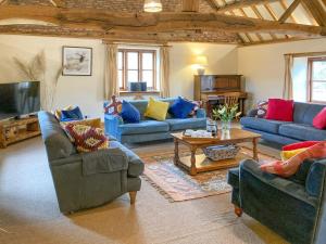 a living room with blue couches and a tv at The Hop Pocket in Bromyard