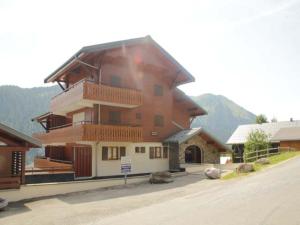 Un grand bâtiment en bois avec un balcon se trouve dans une rue. dans l'établissement Appartement Châtel, 2 pièces, 4 personnes - FR-1-200-175, à Châtel