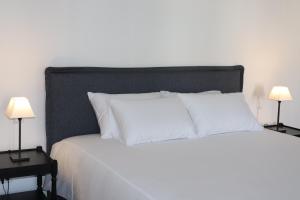 a bedroom with a white bed with two lamps on tables at SOLAR DOS FRADES in Ferreira do Alentejo