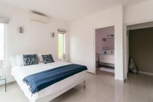 a white bedroom with a large bed with blue sheets at Piscadera Harbour Village in Willemstad
