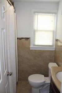 a bathroom with a toilet and a sink and a window at Beautiful place minutes away to New York City . in Teaneck