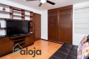 uma sala de estar com uma televisão e um sofá em Apartamento amplio en zona ideal a 5min de WALLMART em Cancún