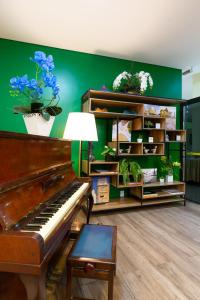 un piano en una habitación con paredes verdes y macetas en Daher Center Hotel, en São Paulo