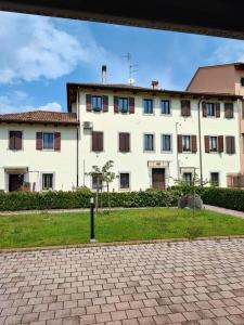 un grande edificio bianco con un prato davanti di La Casa di Priscilla a Fagagna