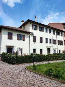 un grande edificio bianco con finestre e un vialetto in mattoni di La Casa di Priscilla a Fagagna