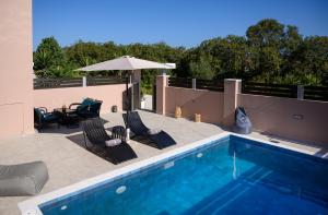 a swimming pool with chairs and an umbrella and a table and an umbrella at Jasmine loft luxury 1 in Kokkini Khanion