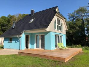 a small house with a deck and a green chair at Ferienhaus am Nationalpark, Klausdorf, ca 250m bis zur Badestelle in Klausdorf Mecklenburg Vorpommern