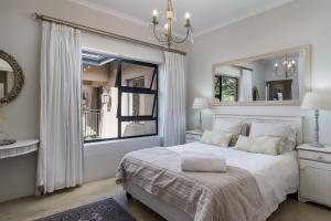 una camera bianca con un grande letto e uno specchio di Boskloof Eco House I a Città del Capo