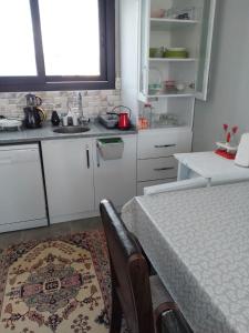 una cucina con armadi bianchi e un tavolo con un tappeto di Flat Close to Sea with Balcony in Seferihisar a Smirne