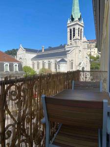 een houten bank voor een kerk met een toren bij Studio refait à neuf en hypercentre avec balcon in Aix-les-Bains