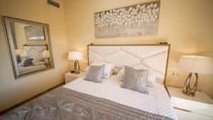 a bedroom with a large bed with two lamps and a mirror at Coto Real Kea 431 in Manilva +25 photos
