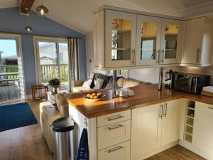 a kitchen with white cabinets and a living room at 3 Bedroom Lodge with Sea Views -Salcombe Retreat in Soar