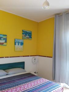 una camera con due letti e una parete gialla di Piazza Ginnasio Affittacamere ad Alghero