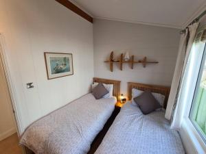 two beds in a small room with a window at 3 Bedroom Lodge with Sea Views -Salcombe Retreat in Soar