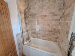 a bathroom with a bath tub with a shower and a sink at 3 Bedroom Lodge with Sea Views -Salcombe Retreat in Soar