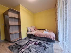 ein Schlafzimmer mit gelben Wänden und ein Bett mit rosa Kissen in der Unterkunft Oasis in Danzig